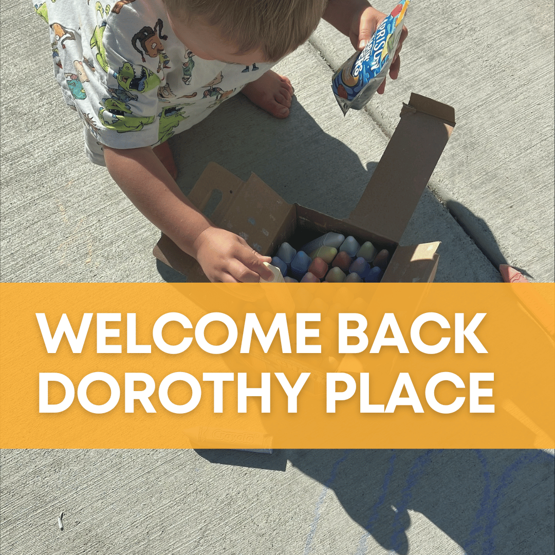 Picture of a small child picking out a piece of chalk as they ready themselves to go make some excellent chalk art. There is an orange banner in the foreground that reads "Welcome Back Dorothy Place"